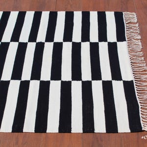 This monochrome wool rug features a bold geometric stripe pattern, perfect for those who love modern and contemporary decor. The handwoven texture enhances its artisanal appeal, while the pure wool construction ensures softness and resilience. Whether placed in a foyer, bedroom, or dining space, this custom-size rug adds a sophisticated and cozy touch to any setting.