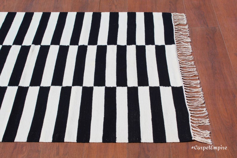 This monochrome wool rug features a bold geometric stripe pattern, perfect for those who love modern and contemporary decor. The handwoven texture enhances its artisanal appeal, while the pure wool construction ensures softness and resilience. Whether placed in a foyer, bedroom, or dining space, this custom-size rug adds a sophisticated and cozy touch to any setting.