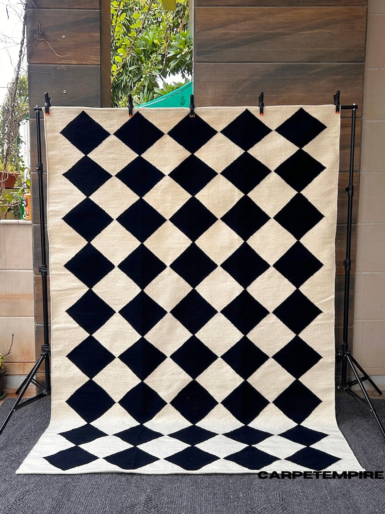 Handwoven wool rug featuring a modern black and white diamond checkered design. This flatweave rug combines Scandi minimalism with timeless craftsmanship, perfect for modern living rooms, bedrooms, or studio spaces. Made from 100% soft wool, it offers warmth, texture, and sophistication to any contemporary or Japandi-inspired interior.