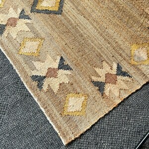 Handwoven natural jute area rug with a beige base, centered cream kilim designs, and a gentle purplish‑black border edge. The flatweave structure ensures low profile and easy cleaning; durable fibre makes it a smart choice for moderate traffic in living spaces or bedrooms. Muted patterning adds warmth and interest without overpowering other design elements.