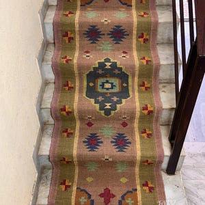 May include: A brown and green patterned rug with a geometric design. The rug is laid on a set of stairs.