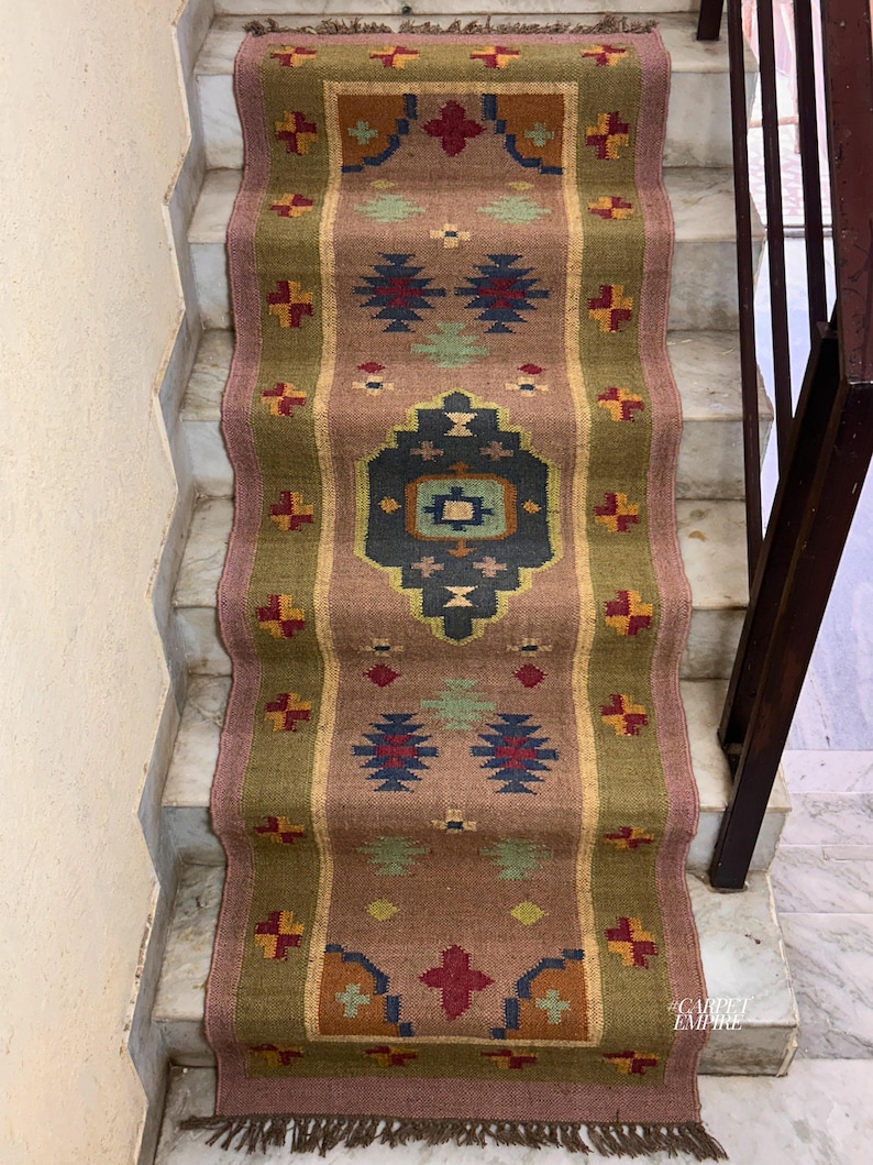 May include: A brown and green patterned rug with a geometric design. The rug is laid on a set of stairs.