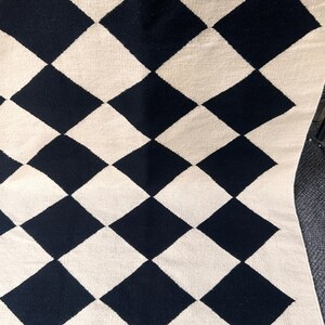 Geometric diamond wool rug featuring black and white check pattern. This modern handmade rug balances luxury and simplicity, offering a soft natural feel for contemporary spaces. Perfect addition to minimal interiors needing visual interest and texture.
