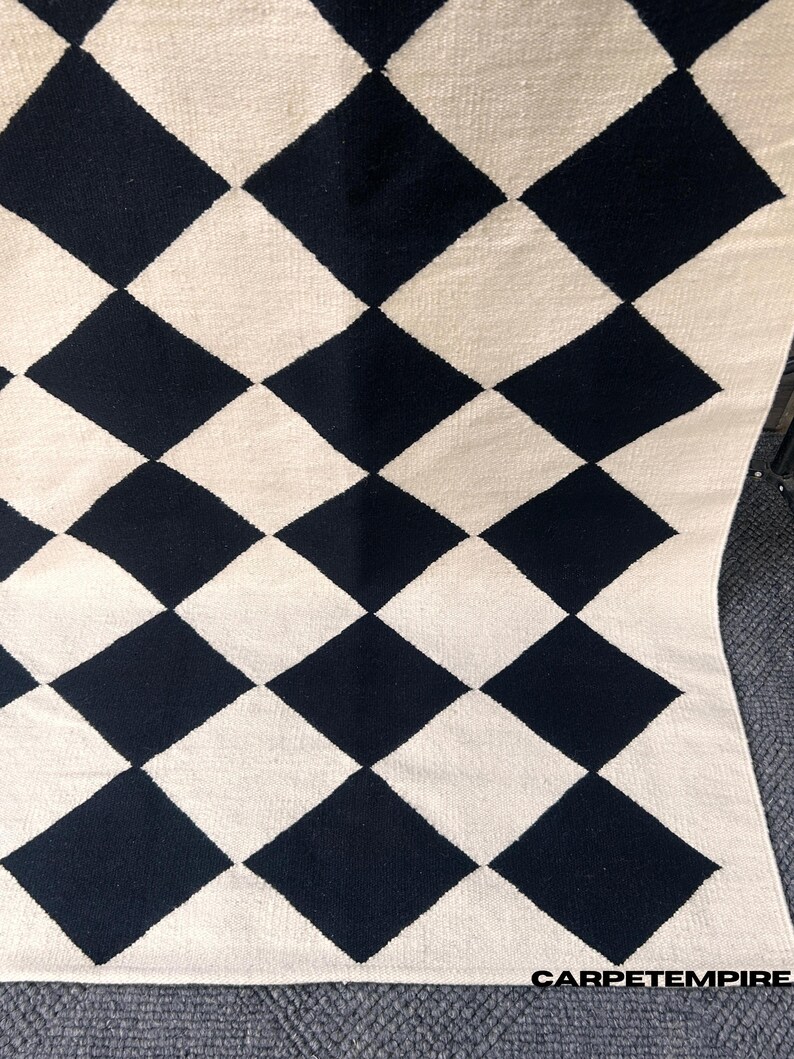 Geometric diamond wool rug featuring black and white check pattern. This modern handmade rug balances luxury and simplicity, offering a soft natural feel for contemporary spaces. Perfect addition to minimal interiors needing visual interest and texture.