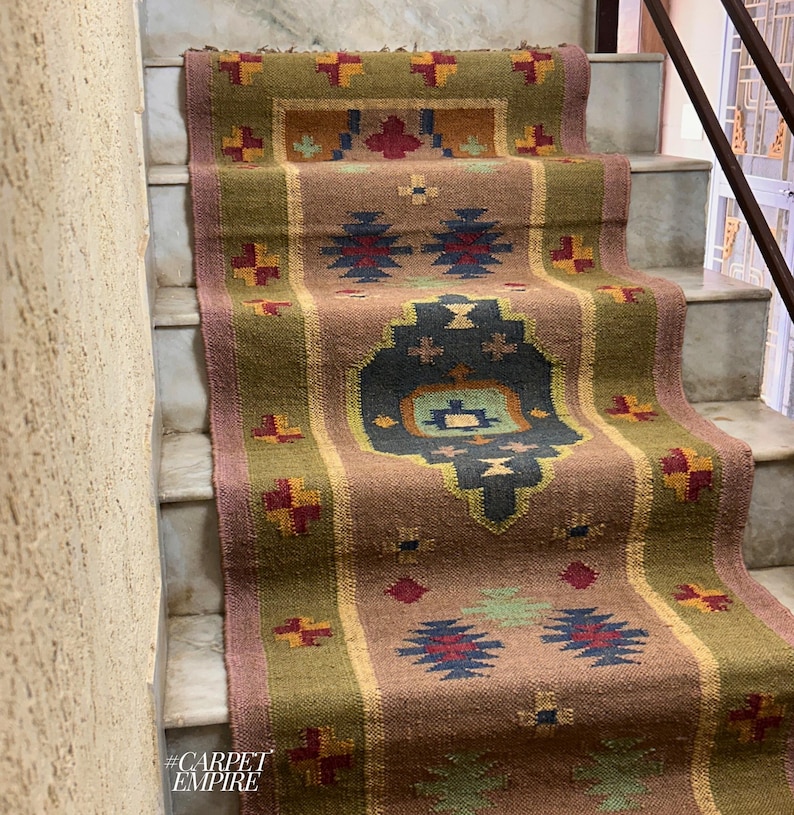 May include: A brown, green, red, and blue patterned rug with a geometric design. The rug is laid out on a set of stairs. The text #CARPETEMPIRE is visible in the bottom left corner of the image.