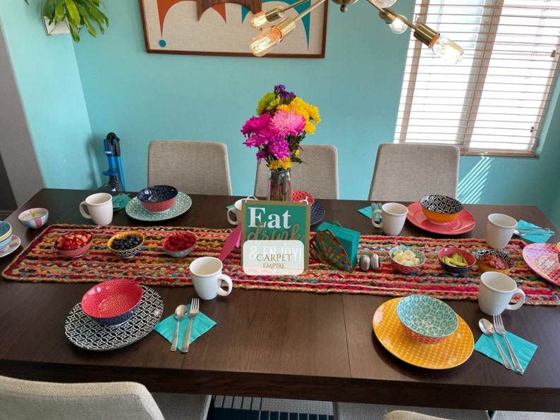 Southwestern style table runner with vivid rainbow hues on a jute base, ideal for boho interiors

Durable handmade jute runner for tables, featuring a mix of cotton fabric strips and earthy texture