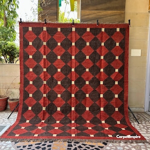 Artisan flatweave kilim rug with a geometric tribal design in earthy red and ochre tones. Made from a high-quality wool and jute blend, this eco-friendly rug is handmade using time-honored dhurrie weaving methods. Its rich colors and low-pile texture make it a versatile choice for hallways, bedrooms, or small sitting areas.
