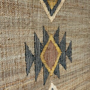 Flatwoven jute kilim rug with warm beige ground, soft cream motif details, and a defining dark border in purplish‑black. Crafted from natural jute fibers, this rug adds natural texture underfoot and a handcrafted aesthetic. Ideal for rooms with light wood floors, linen textiles, or neutral palettes, giving depth through geometric pattern and natural material without bold or bright tones.