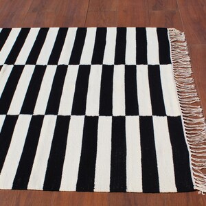 A perfect mix of functionality and aesthetics, this black and white geometric rug is a must-have for anyone seeking a modern yet cozy ambiance. The handwoven wool fibers provide natural insulation, making it a comfortable addition to any bedroom or workspace. Its timeless striped pattern adds a contemporary feel, ideal for elevating neutral-toned interiors.