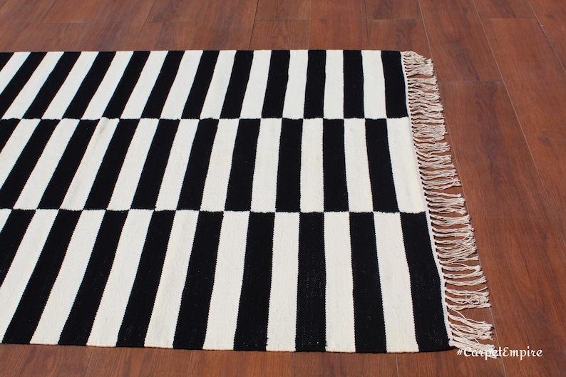 A perfect mix of functionality and aesthetics, this black and white geometric rug is a must-have for anyone seeking a modern yet cozy ambiance. The handwoven wool fibers provide natural insulation, making it a comfortable addition to any bedroom or workspace. Its timeless striped pattern adds a contemporary feel, ideal for elevating neutral-toned interiors.