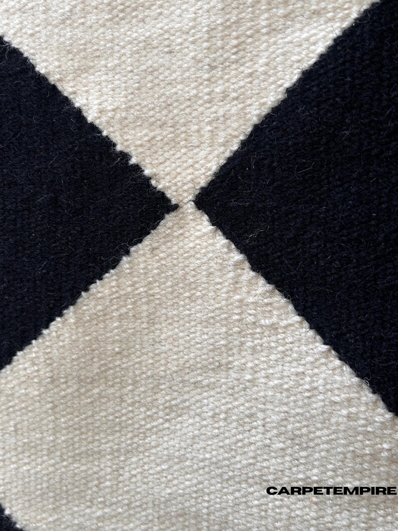 Handmade black and white check wool rug with geometric diamond patterns. The soft wool fibers and flatweave texture create a cozy yet clean finish, ideal for living rooms or bedrooms styled in Scandinavian or modern decor themes.