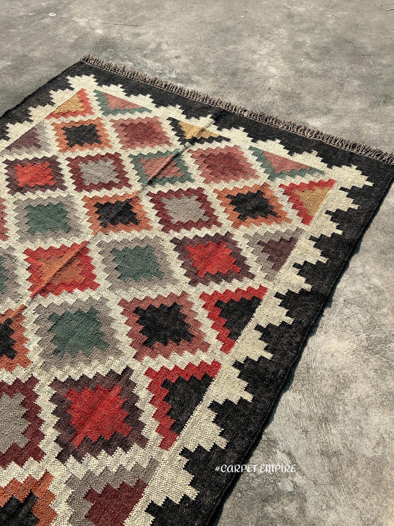 Jute Wool Rug handloomed in traditional flatweave featuring stepped-diamond motifs in rust, ochre, sage and plum — a Kilim Area Rug crafted in India.