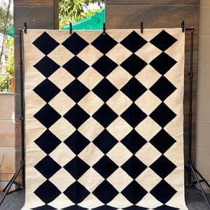 Elegant wool area rug with black and white checkered design, handwoven by artisans using traditional flatweave methods. The 100% wool fiber provides natural softness and durability, making it a perfect fit for Scandi, Japandi, or minimalist home styles.