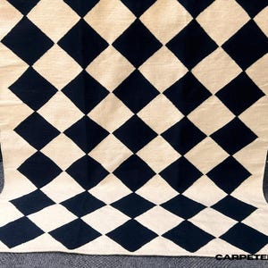 Elevate your space with this Modern Wool Rug, a handwoven geometric check design that blends timeless craftsmanship with minimalistic Scandi style. Featuring a black and white diamond checkered pattern, this flatweave rug is crafted from 100% natural wool, making it both soft and durable