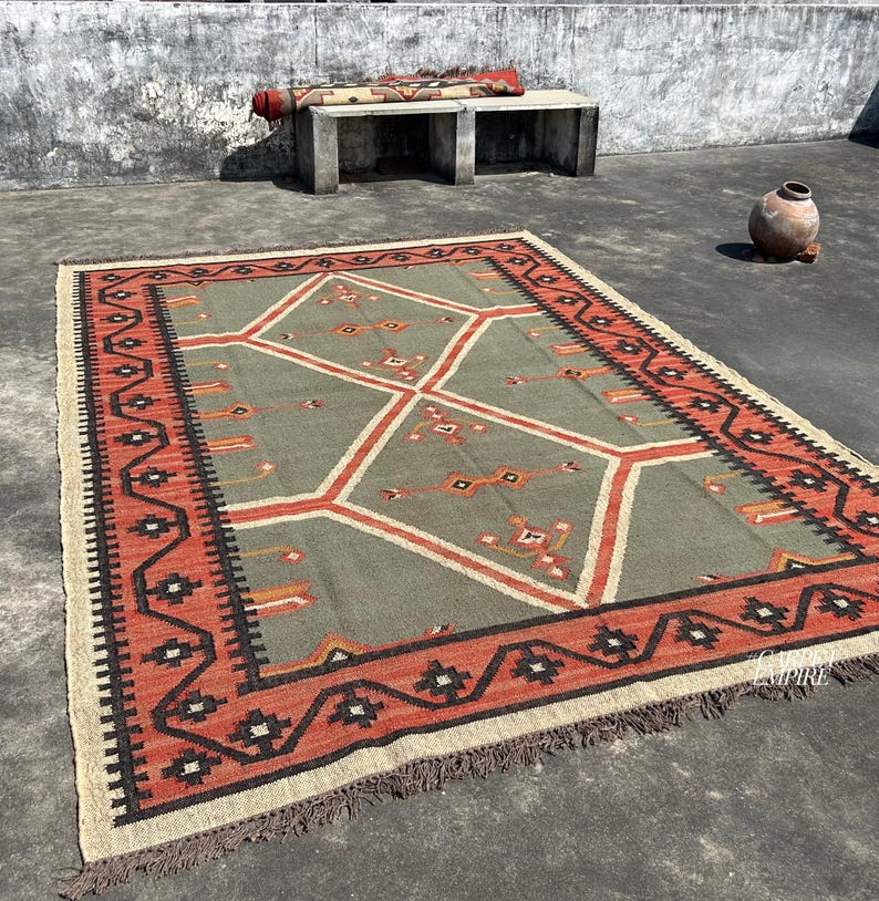 Handmade sage green kilim area rug with terracotta border and stacked diamond medallions. Tribal cross gold black accents. Wool jute flatweave with fringe. Custom sizes.