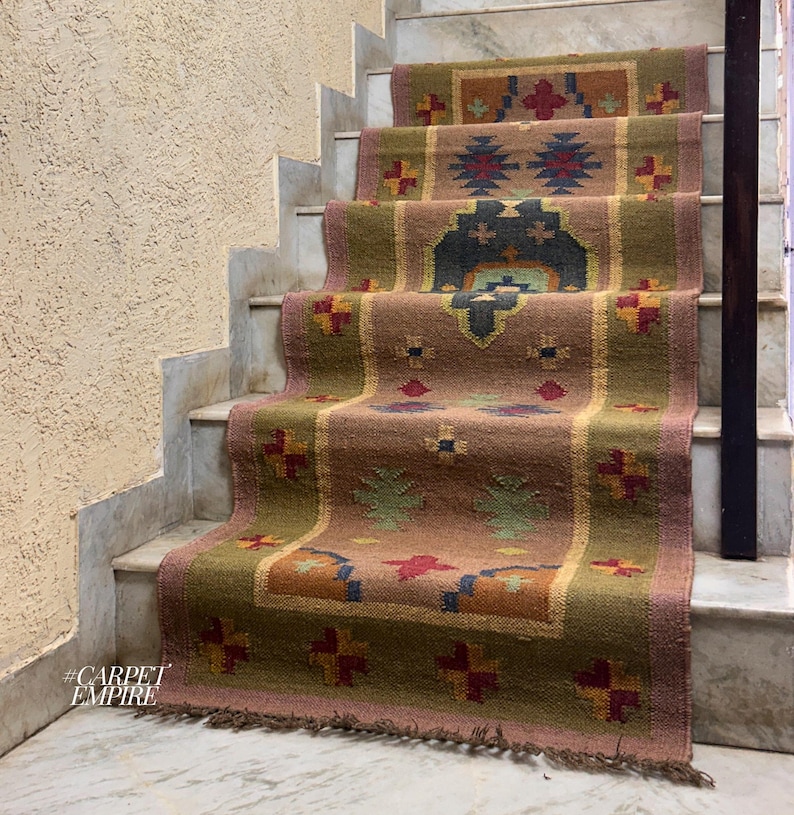 May include: A brown, green, and red patterned rug with fringe on the bottom edge. The rug is laid out on a set of stairs.