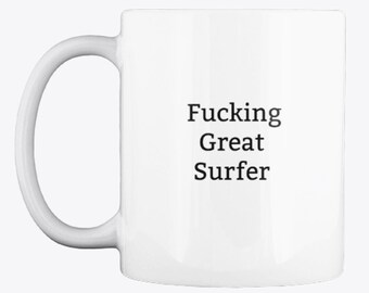 May include: White ceramic coffee mug with black text that reads "Fucking Great Surfer".