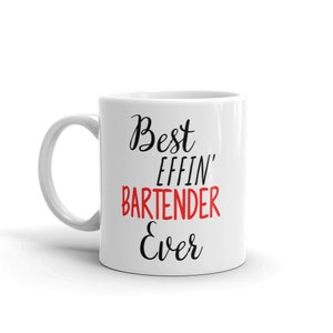 Pode incluir: Caneca de cerâmica branca com texto preto que diz "Best Effin' Bartender Ever". A palavra "Bartender" está em vermelho.