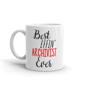 Könnte beinhalten: Weiße Keramiktasse mit schwarzem Text, der "Best Effin' Archivist Ever" lautet. Das Wort "Effin'" ist rot.