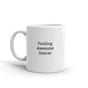 May include: White ceramic coffee mug with black text that reads "Fucking Awesome Dancer".
