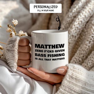 May include: White ceramic mug with the name "MATTHEW" in bold black letters. The mug also features the text "ZERO F*CKS GIVEN BASS FISHING IS ALL THAT MATTERS". The top of the mug has the text "PERSONALIZED FILL IN YOUR NAME".