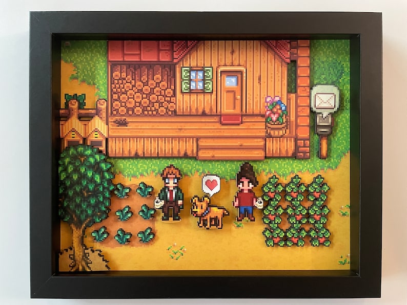 May include: Framed pixel art diorama showing a wooden house, crops, and characters. The artwork features a dog with a heart bubble, two people, and a mailbox. The colour palette includes greens, browns, and yellows.