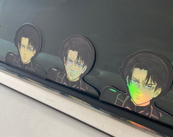 May include: Three black and white anime character stickers with holographic accents. The stickers are on a car window.