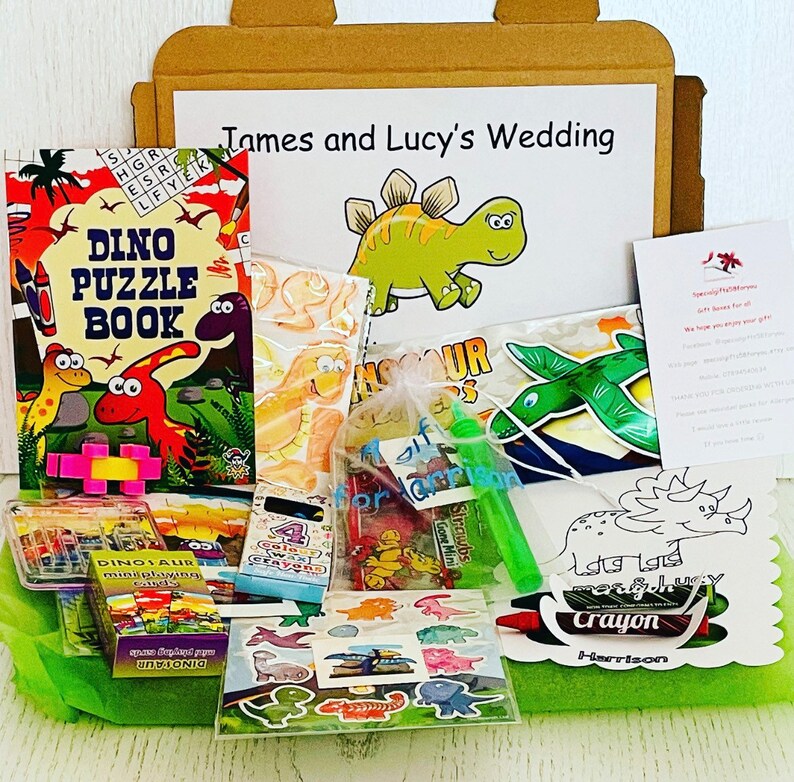 May include: A gift box filled with dinosaur-themed party favors. Includes a puzzle book, crayons, stickers, and other small toys. The box is decorated with a dinosaur illustration and the text "James and Lucy's Wedding".