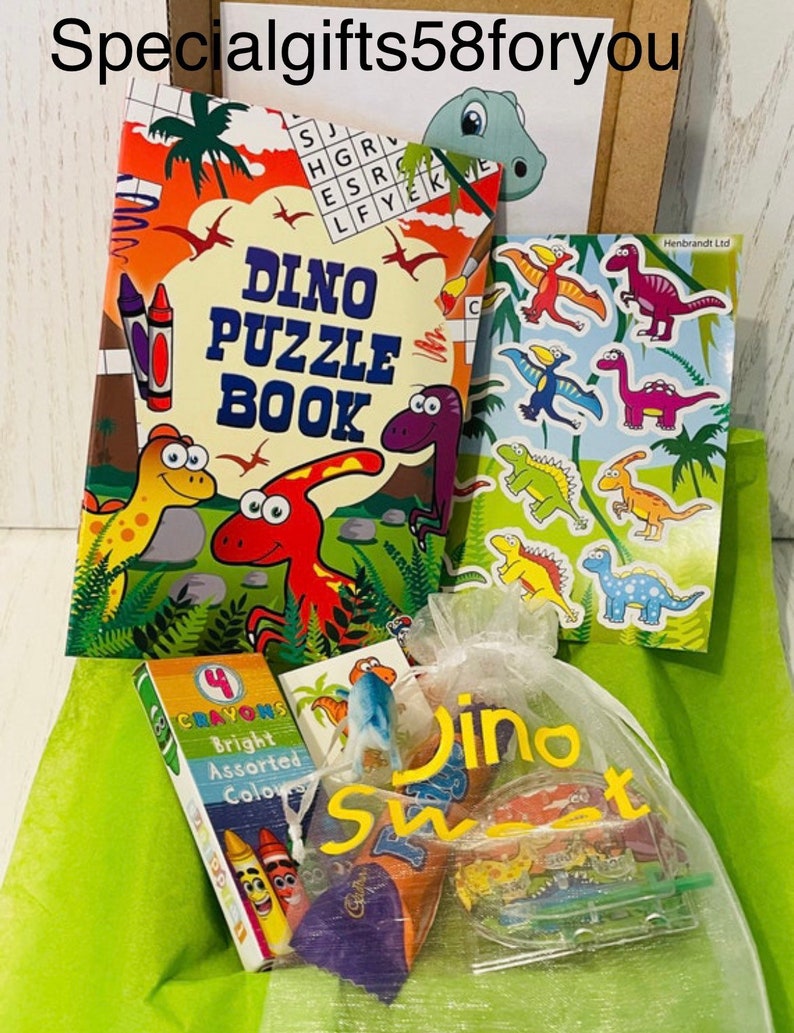 May include: A collection of dinosaur-themed items, including a puzzle book, stickers, crayons, and a bag of sweets. The puzzle book features colorful illustrations and the text "DINO PUZZLE BOOK". The bag is labeled "Dino Sweet".