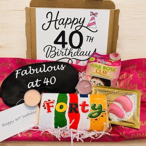 May include: A birthday gift box containing a black sleep mask with the text Fabulous at 40, a 7th Heaven Pink Rose Clay face mask, a gold Collagen Crystal Eye Mask packet, two small tea light candles, and a candy bar labeled FORTY.