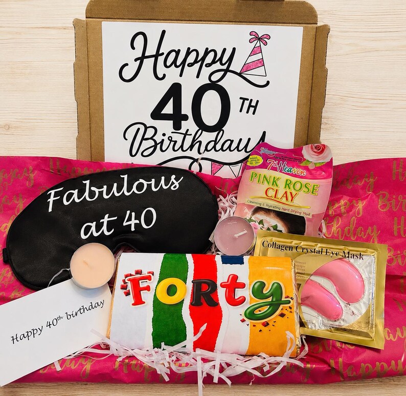 May include: A birthday gift box containing a black sleep mask with the text Fabulous at 40, a 7th Heaven Pink Rose Clay face mask, a gold Collagen Crystal Eye Mask packet, two small tea light candles, and a candy bar labeled FORTY.