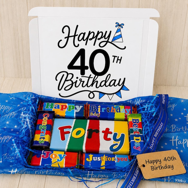 May include: A white gift box with the text Happy 40th Birthday and a blue party hat icon. Inside are chocolate bars wrapped in colorful paper with text including Congrats, Forty, Best Day, Joy, and Just for you, plus a brown gift tag.