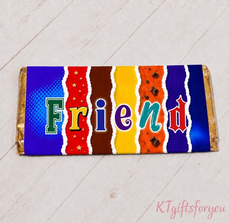 May include: A wrapped chocolate bar with the word "FRIEND" in colorful letters. The packaging has a blue, red, brown, yellow, and purple design with a torn paper effect. The bar is on a light wood surface.