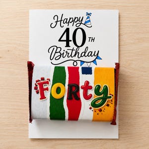 May include: A rectangular birthday card with the text Happy 40th Birthday and a blue party hat icon. Attached is a candy bar wrapper featuring vertical stripes of white, green, red, and yellow, with the word Forty in colorful 3D lettering.