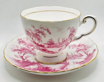 Può includere: Un set da tè in porcellana bianca e rosa con bordo dorato. La tazza e il piattino presentano un delicato motivo floreale rosa e bianco.