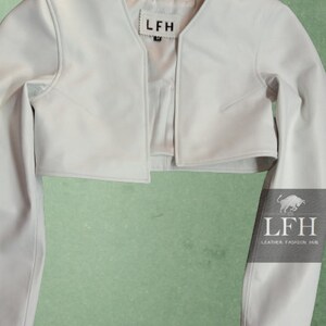 May include: A white cropped leather jacket with long sleeves. The jacket has a V-neck and a label that says "LFH" on the front.