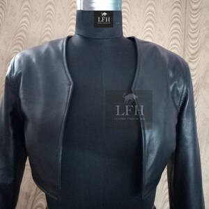 May include: A black leather cropped jacket with long sleeves. The jacket has a V-neck and a simple design. The label "LFH Leather Fashion Hub" is visible on the front.