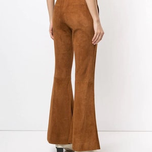 Pode incluir: Cal&ccedil;a flare marrom de camur&ccedil;a com cintura alta e corte reto.