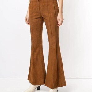 Pode incluir: Cal&ccedil;a de camur&ccedil;a marrom de boca de sino com cintura alta e corte reto. A cal&ccedil;a tem z&iacute;per e bot&atilde;o.