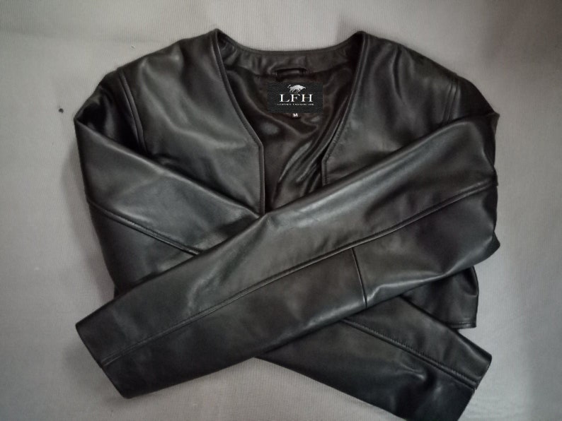 May include: A black leather jacket with a V-neck and long sleeves. The jacket has a small label on the front that says "LFH".