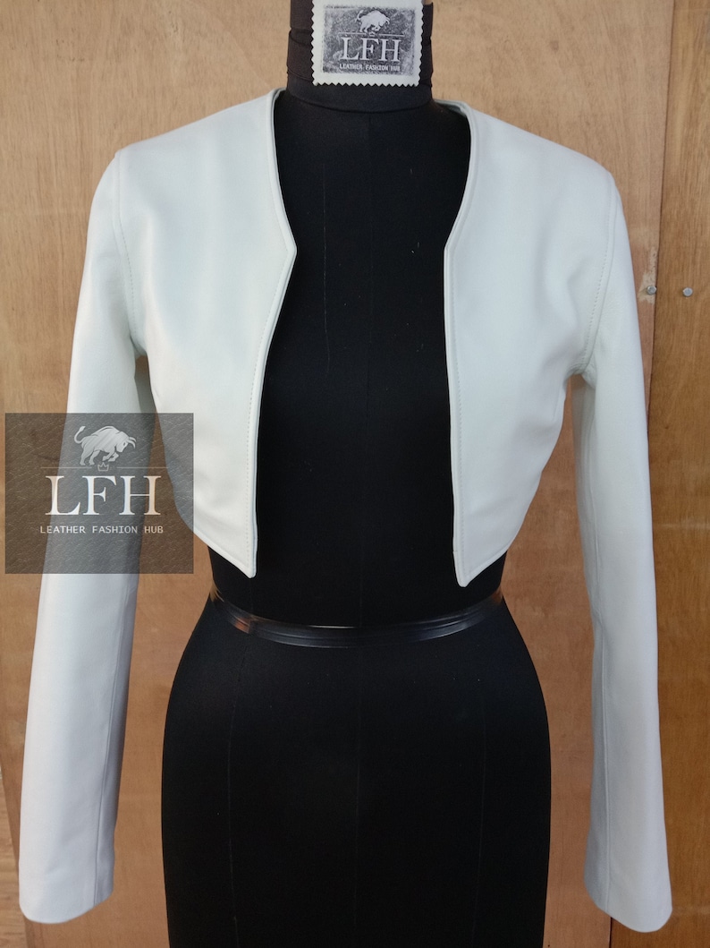 May include: A light green cropped leather jacket with long sleeves. The jacket has a V-neck and is shown on a mannequin.