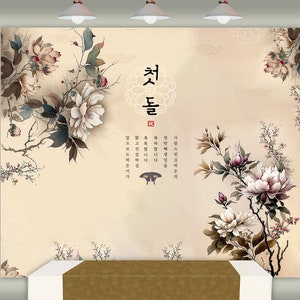 May include: A beige background with a floral design featuring white flowers and green leaves. The text "첫돌" is written in black calligraphy in the center of the image. The text translates to "First Birthday" in English.