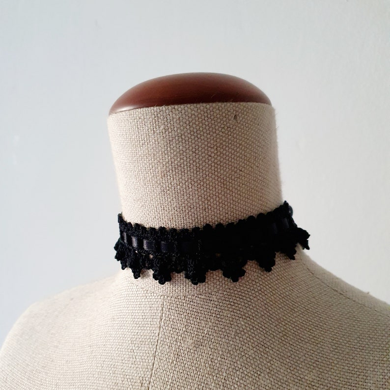 May include: A black lace choker necklace on a white mannequin.