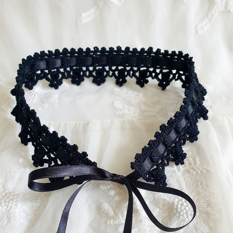May include: Black crocheted lace choker with a black satin ribbon tie. The choker is delicate and feminine, perfect for adding a touch of elegance to any outfit.