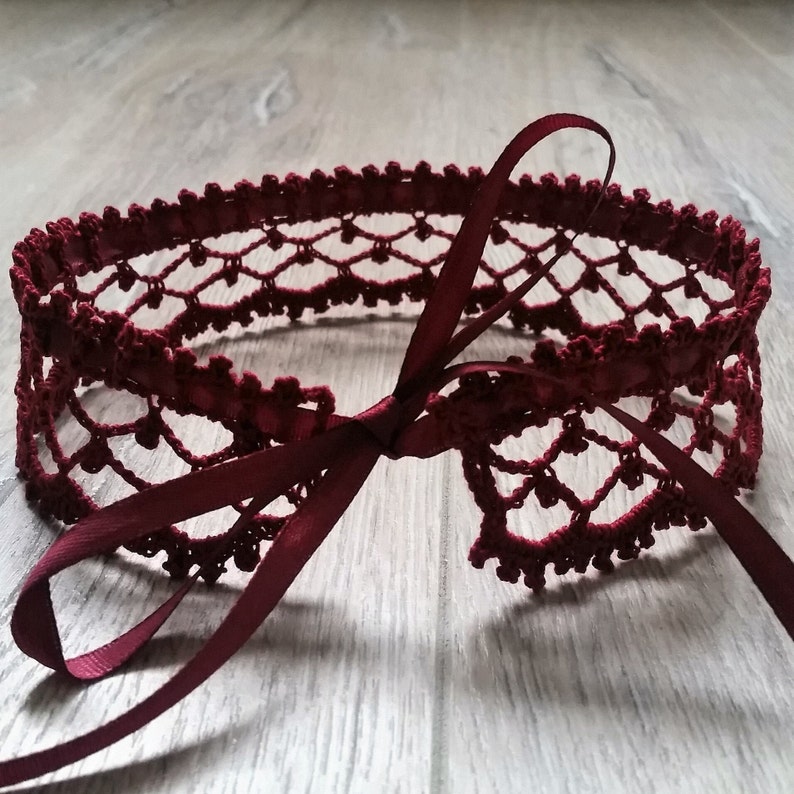 May include: A burgundy crocheted lace choker with a matching satin ribbon tie.