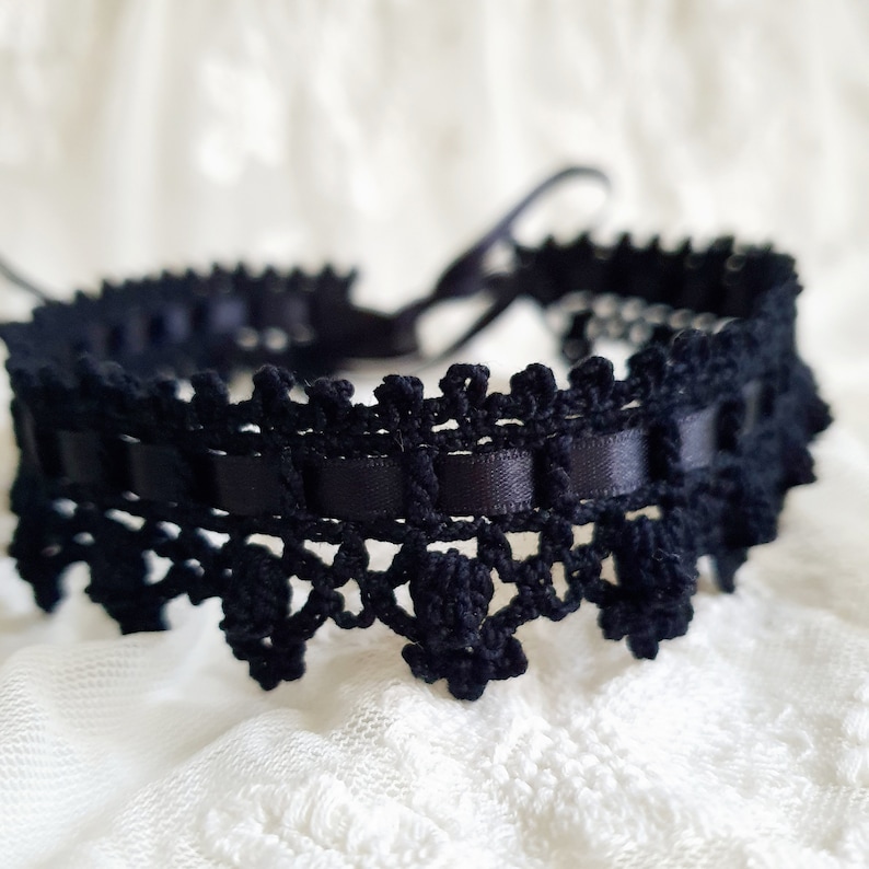 May include: Black lace choker with a satin ribbon detail. The choker is tied with a ribbon at the back.