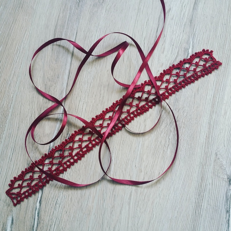 May include: A red crocheted lace trim with a red satin ribbon tied around it.