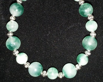 May include: A green jade beaded bracelet with silver accents. The beads are round and have a smooth, polished finish.