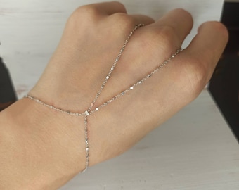 May include: A silver chain bracelet with a delicate design. The bracelet is worn on a hand and extends up the arm, creating a unique and stylish look.