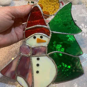 Snowman with Hat and Scarf next to Evergreen Stained Glass Sun Catcher